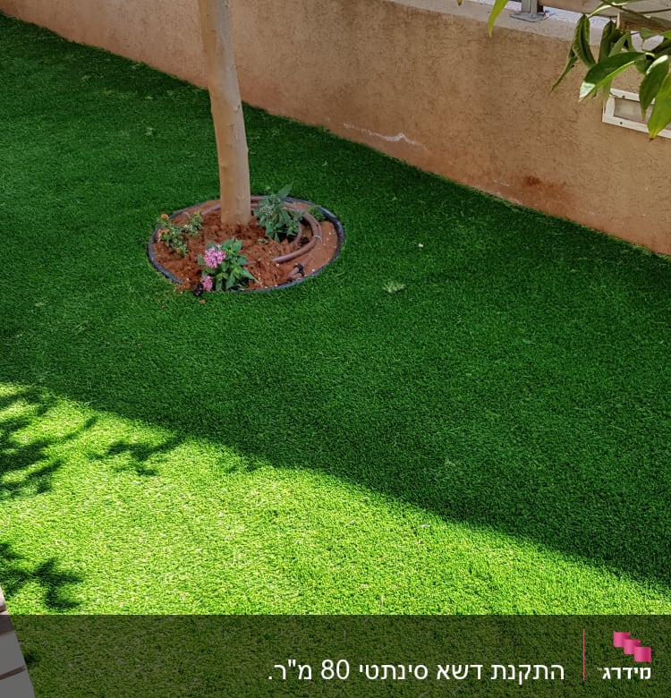 דשא סינתטי עם עץ ופרחים בגינה קטנה